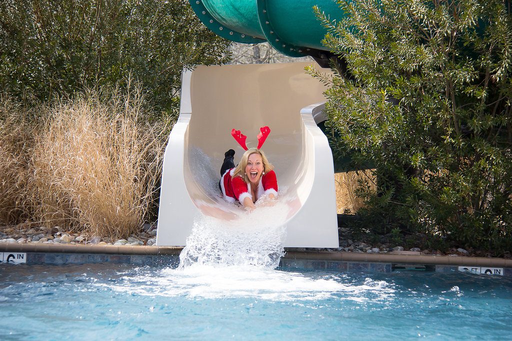 Woman in santa outfit sliding down water slide