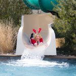 Woman in santa outfit sliding down water slide