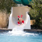 Woman in santa outfit sliding down water slide