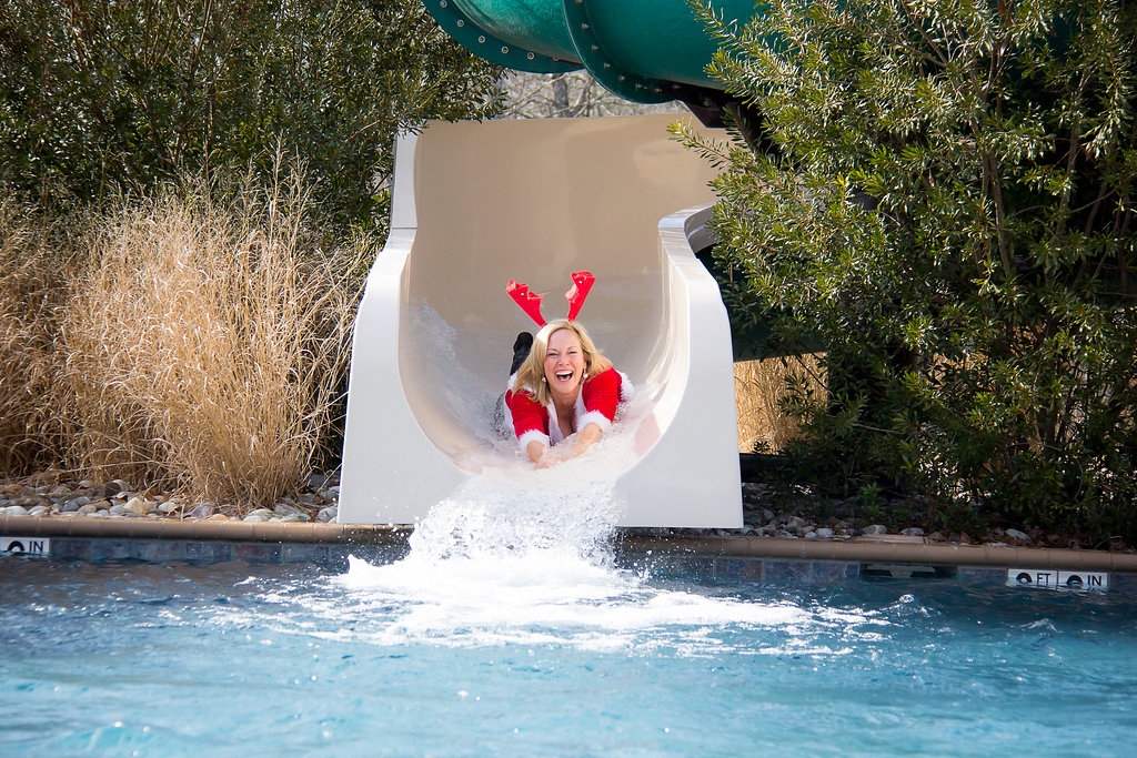 Woman in santa outfit sliding down water slide